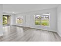 Bright living room with light gray wood floors and lots of natural light from the large windows at 5008 Vanguard St, Orlando, FL 32819