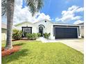 Beautiful single-story home with a well-manicured lawn and black-trimmed facade in a sunny setting at 132 Canary Island Cir, Davenport, FL 33837