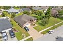 An aerial shot of a single-story home showcasing the brick driveway, well-manicured lawn, and surrounding neighborhood at 311 Bentley Oaks Blvd, Auburndale, FL 33823
