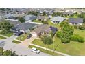 Aerial view of a home with solar panels, a brick driveway, and a well-kept lawn in a suburban neighborhood at 311 Bentley Oaks Blvd, Auburndale, FL 33823