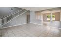 Open-concept living room features tile flooring, a staircase, and neutral gray wall paint at 811 Abbeville Ct, Kissimmee, FL 34759