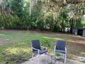 Backyard area with a patio and furniture; view of the large fenced yard surrounded by mature trees at 309 Sunnyside Ln, Debary, FL 32713