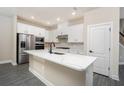 Bright kitchen with white cabinetry, stainless steel appliances, and a large island with quartz countertop at 7728 Somersworth Dr, Kissimmee, FL 34747