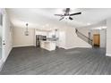 Spacious open-concept living room and kitchen area with modern gray wood flooring and elegant light fixtures at 7728 Somersworth Dr, Kissimmee, FL 34747