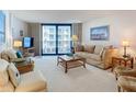 Well-lit living room with comfortable seating, a glass coffee table, and a balcony at 1415 Ocean Shore Blvd # 309, Ormond Beach, FL 32176