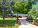 Charming brick home featuring a long driveway, mature trees, and lush landscaping at 106 N Frederick St, Pierson, FL 32180