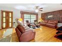 Inviting living room with brick accent wall, hardwood floors, and leather furniture, illuminated by natural light at 106 N Frederick St, Pierson, FL 32180