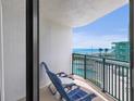Balcony view of the beach and pool below features two lounge chairs and small table at 2555 S Atlantic Ave # 207, Daytona Beach Shores, FL 32118