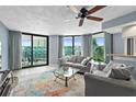 Open living room with many windows, light gray modern furniture, and sliding glass doors to a balcony at 2555 S Atlantic Ave # 207, Daytona Beach Shores, FL 32118