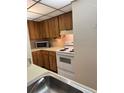 Functional kitchen with wood cabinets and white appliances at 110 Cypress Woods Ct # 7D, Deltona, FL 32725