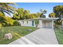 Charming single-story home featuring a well-maintained lawn, a vibrant blue door, and a covered parking area at 522 Powers Ave, Port Orange, FL 32127