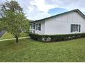 Well-maintained single-story home featuring green shutters, a lush lawn, and mature landscaping at 201 N Hill Ave # 150, Deland, FL 32724