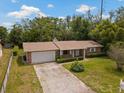 Aerial view of a cozy brick house with an attached garage, driveway, and green lawn at 1639 Templewood Ave, Deltona, FL 32725