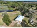 Aerial view of a small home with a light metal roof surrounded by lush greenery and a pond at 353 Vannote Rd, Pierson, FL 32180