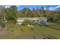 Exterior shot of a charming home, with lush green lawn and mature trees surrounding at 227 N Putnam Grove Rd, Oak Hill, FL 32759