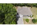 A serene aerial view of a single-Gathering home with a paved driveway and a gray roof amidst lush greenery at 1600 Lady Fern Trl, Deland, FL 32720