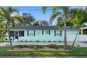 Well-maintained light blue home with lush landscaping, palm trees, and a spacious front yard at 1146 Riverside Dr, Daytona Beach, FL 32117