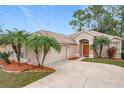 Tan house with palm trees, a two-car garage, and a manicured lawn at 189 Perfect Dr, Daytona Beach, FL 32124
