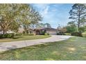 Beautiful single-story home with a circular driveway, mature trees, lush landscaping, and an attached garage at 376 Hampton Hills Ct, Debary, FL 32713