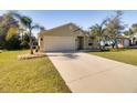Tan one-story house with a two-car garage and palm trees at 981 Wilmington Dr, Deltona, FL 32725
