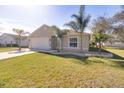 Tan house with white garage door, landscaping, and palm trees at 981 Wilmington Dr, Deltona, FL 32725