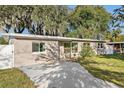Newly renovated tan brick house with a white fence, driveway and landscaping at 118 N Sunland Dr, Sanford, FL 32773