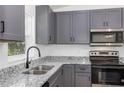 Bright kitchen showcasing gray cabinetry, granite countertops, and a stainless steel sink at 1205 2Nd St, Orange City, FL 32763