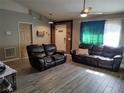 Living room features wood-look tile floors, two brown leather couches, and a ceiling fan at 1615 18Th St, Orange City, FL 32763