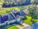 An aerial view of a villa with a large yard, lush trees, and a large driveway and garage at 55 Fairway Dr # 3D, Debary, FL 32713