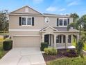 Tan two-story house with black shutters, a two-car garage, and a landscaped yard at 10025 Scottish Pines Ct, Orlando, FL 32832