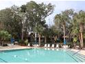 Community pool with lounge chairs and umbrellas, surrounded by palm trees at 130 Jasmine Woods Ct # 15C, Deltona, FL 32725