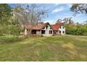 Exterior view of a charming home featuring a lush green lawn, trees, and a distinctive red roof at 2170 Wilmhurst Rd, Deland, FL 32720