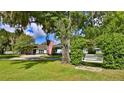 Landscaped front yard with a white swing bench under a large oak tree at 2530 E New York Ave, Deland, FL 32724