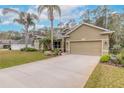 Tan house with palm trees, landscaped lawn, and two-car garage at 34 Black Creek Way, Ormond Beach, FL 32174