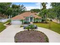 Lovely home featuring a manicured lawn, mature trees and landscaping, plus a classic car in the drive at 39 Ormond Green Blvd, Ormond Beach, FL 32174