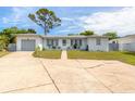 Front view of a single-story home with a light-colored exterior and a spacious driveway at 469 S Halifax Dr, Ormond Beach, FL 32176