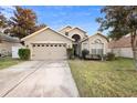 Tan house with a two-car garage and a well-maintained lawn at 3125 Wood Rose Way, Deltona, FL 32725