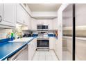 Kitchen features white cabinets, blue countertops, stainless steel appliances, and tiled floor at 1224 S Peninsula Dr # 511, Daytona Beach, FL 32118