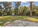 Large backyard with established trees and landscaping, storage shed, and play set at 1240 W Voorhis Ave, Deland, FL 32720