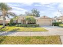 Single-story home with landscaped yard, attached garage, and palm trees at 555 Morgan Wood Dr, Deland, FL 32724