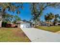 Wide shot of a single-story home featuring a long driveway leading to a two-car garage and mature trees in the front yard at 709 Lone Oak Dr, Port Orange, FL 32127