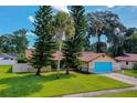 Charming home with vibrant blue garage door and stone accents, complemented by mature trees and well-manicured lawn at 949 Tall Pine Dr, Port Orange, FL 32127