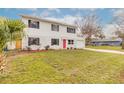 Two-story home, showcasing the front yard with lush greenery and a bright red front door at 1195 10Th St, Daytona Beach, FL 32117