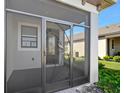 View of the screened-in front porch featuring custom door and tile flooring at 1372 Lombardi Ct, Poinciana, FL 34759