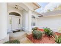 Inviting front entrance with decorative columns, an arched window, and a meticulously landscaped garden at 163 Chrysanthemum Dr, Ormond Beach, FL 32174