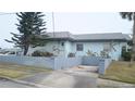 Side view of a light blue house with a low cinder block wall and driveway at 2201 S Peninsula Dr, Daytona Beach, FL 32118