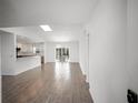 Bright living room featuring wood-look tile floors, an open layout, and access to the kitchen and outdoor area at 24 Sea Gull Dr, Ormond Beach, FL 32176