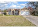 A charming tan single-story home with a well-manicured front lawn and a spacious two-car garage at 893 S Dean Cir, Deltona, FL 32738