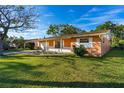 Street view of a cozy single-story home with a lush green lawn and mature trees at 1216 Sunland Rd, Daytona Beach, FL 32114