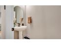 Cozy half bathroom featuring a pedestal sink, round mirror and neutral color palette at 221 Aston Grande Dr, Daytona Beach, FL 32124